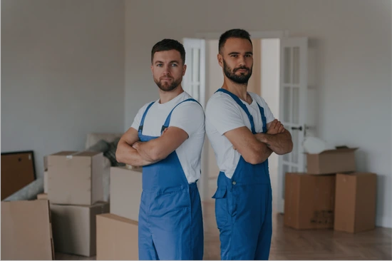 zwei Arbeiter einer Umzugsfirma, die in die Kamera schauen